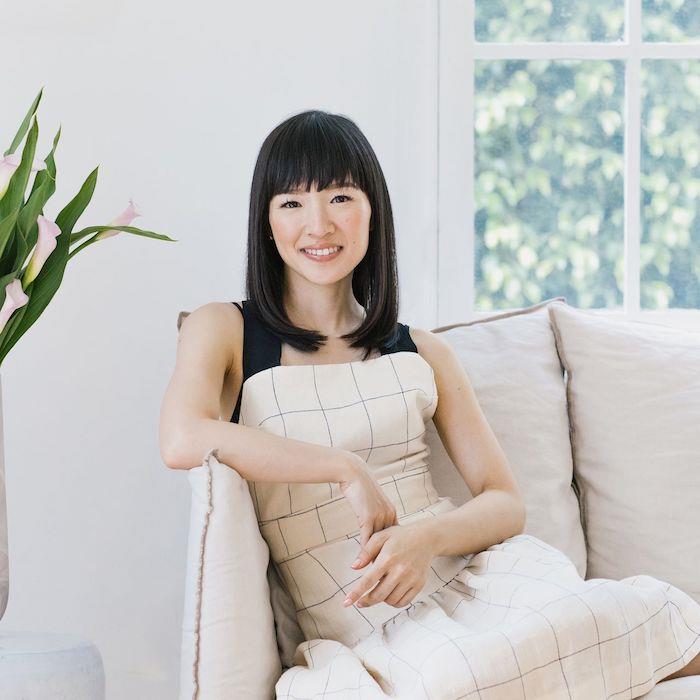 marie kondo v fotelju konmari metoda zelena rastlina na desni