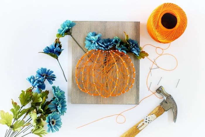 „Pasidaryk pats“ Helovino idėja su gražiai dekoruota medine lenta, pagaminta iš oranžinės ištemptos vielos ir mėlynų dirbtinių gėlių moliūgo formos
