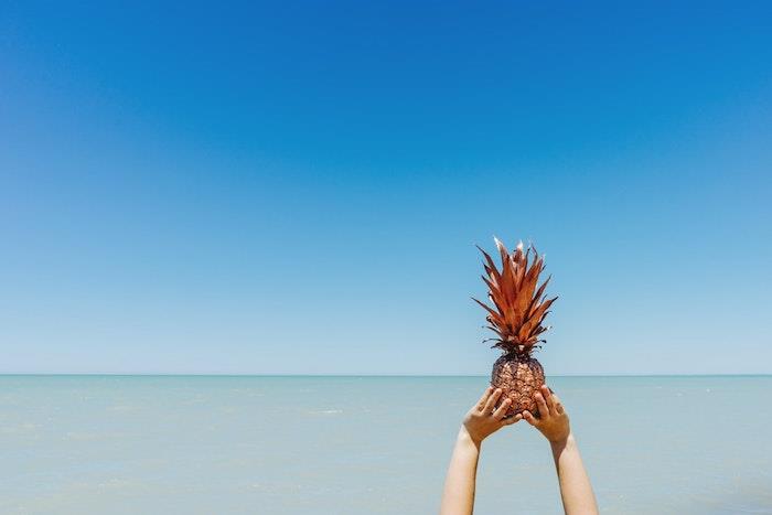 Bir çocuğun elinde renkli ananas, berrak su ve berrak mavi gökyüzü, harika duvar kağıdı, göksel manzara, kaliteli fotoğraf