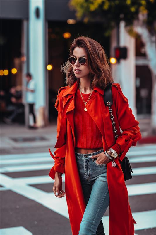 Klasikiniai džinsai ir trumpas raudonas marškinių viršus, suporuotas su elegantišku raudonu paltu, apvalūs akiniai nuo saulės, modernūs papuošalai