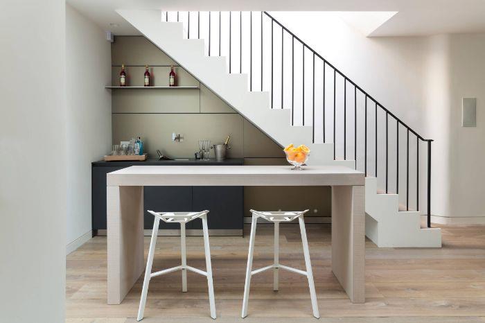 kuhinjska omara antracitno sive barve in sivi paneli beli osrednji otok z belimi stoli kuhinja pod stopnicami majhna kuhinja