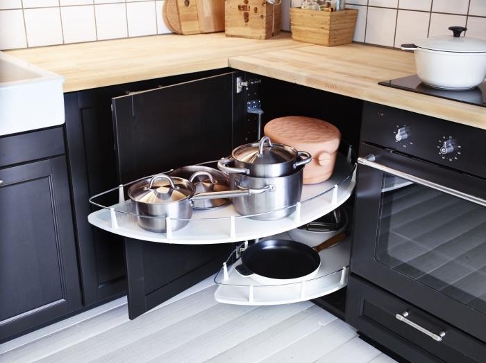 žema virtuvinė kampinė spintelė su dviem melamino stalviršiais, kad būtų galima lengvai pasiekti virtuvės indus, žemos medinės ir juodos virtuvės spintelės, kontrastingos baltoms sienoms ir grindims