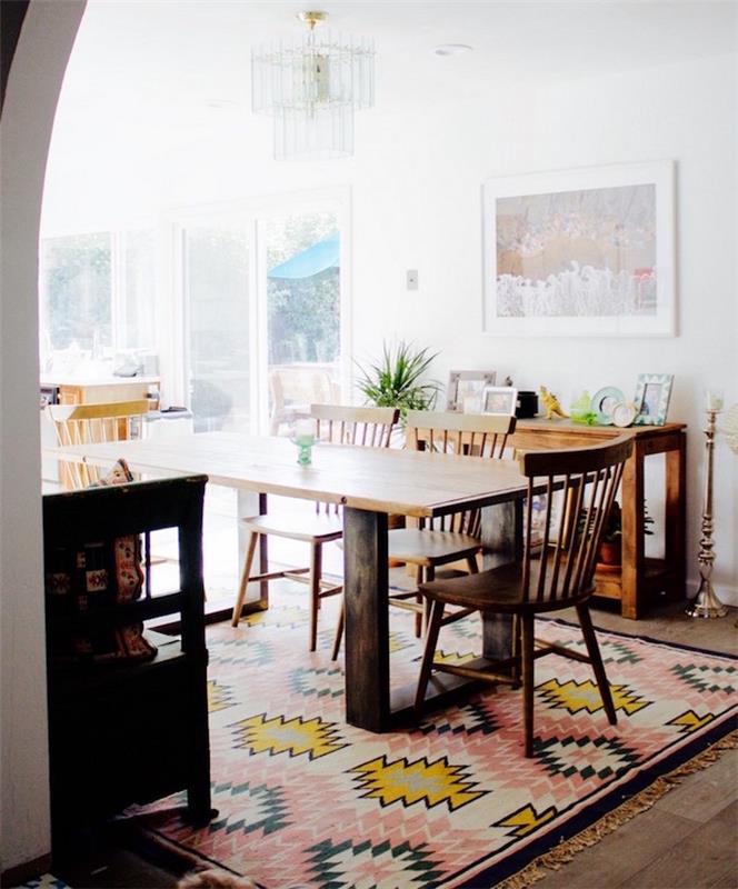 Skandinavska dnevna soba z leseno jedilno mizo na barvni preprogi in belimi stenami