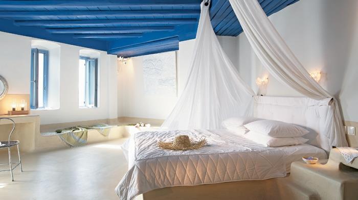 Grški dekor, marmorna tla, okroglo ogledalo, sveče, svetlo modre polkne, postelja z baldahinom