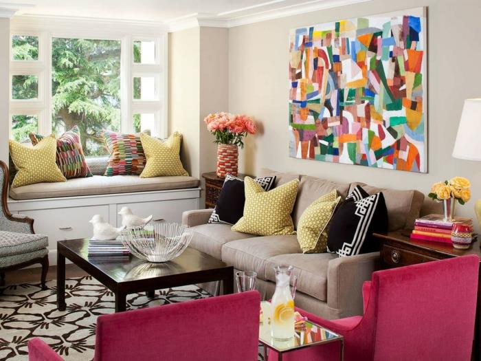 sivo pohištvo, roza naslanjači, originalne vzorčaste preproge, okrasne blazine, abstraktno slikarstvo, temna lesena miza