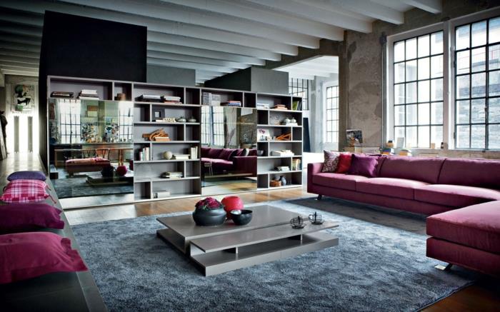 pramoninio deko idėja, violetinės pagalvėlės, dideli veidrodžiai, kampinė sofa, pilkas kavos staliukas, minkštas kilimas, lubos su sijomis