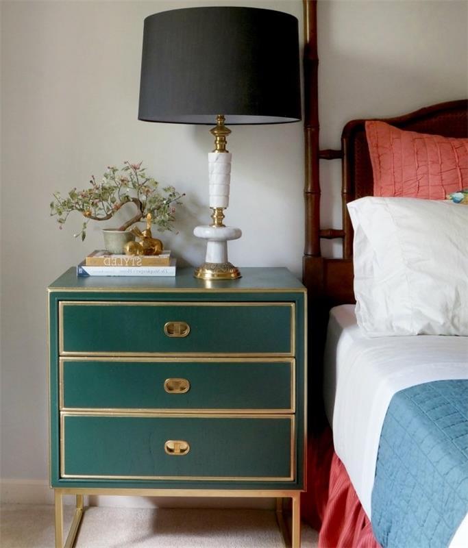 nočna omarica s shranjevanjem, prebarvana v smaragdno zeleno, belo, modro in rdečo posteljnino, črna nočna svetilka z zlatim podnožjem, bež preproga