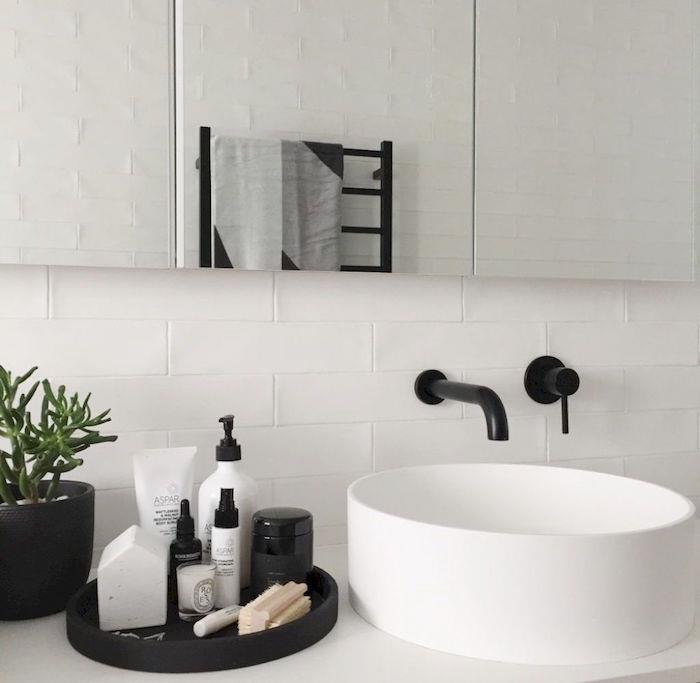okrogel umivalnik z mat črno armaturo v kopalnici z belimi ploščicami in velikim ogledalom