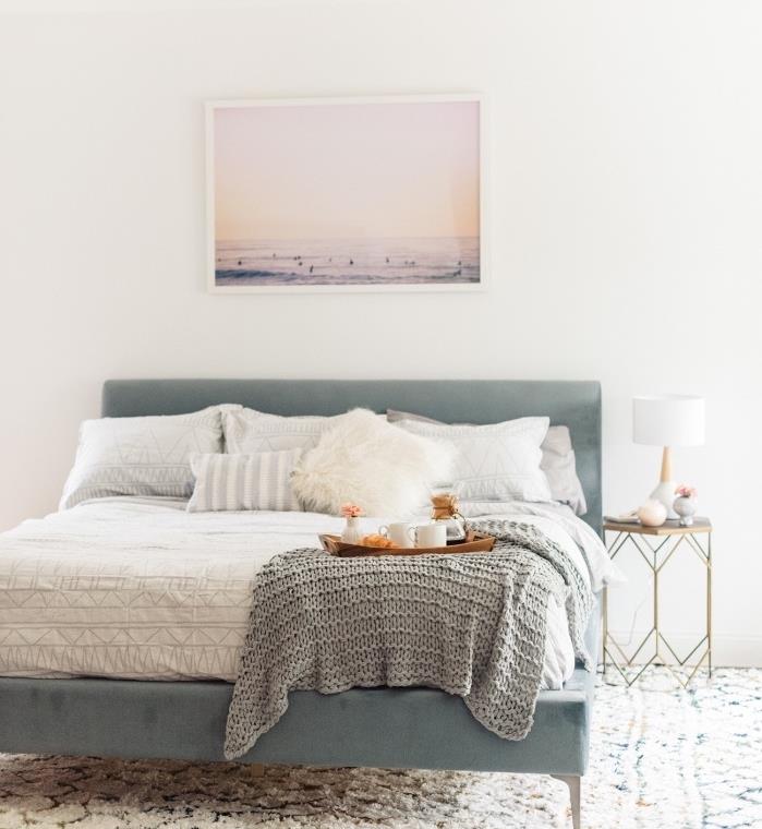 İskandinav mobilyaları, büyük mavi gri yatak, beyaz nevresimler, gri battaniye, deniz manzarası fotoğraf dekoru, geometrik desenli beyaz halı