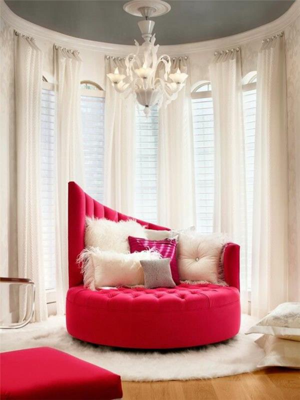 baroko stiliaus baldų apvali raudona dygsniuota sofa su balta liustra ir baltomis skaidriomis užuolaidomis