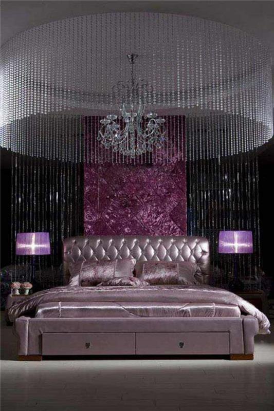 Lila yatak odasında büyük kristal avize ve lila aydınlatma armatürleri ile Barok mobilyalar