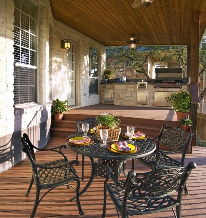terasos apdaila su apvaliu stalu ir kaustytomis kėdėmis, pavyzdinė lauko kriauklė ant akmens ir nerūdijančio plieno virtuvės zona