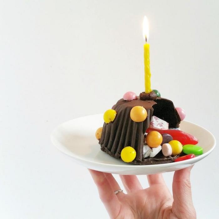 mini votla čokoladna pinata torta, ki vsebuje različne sladkarije, z eno samo svečo