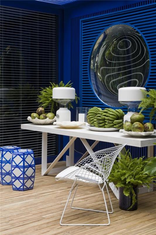 didelis išgaubtas veidrodis elektriniame mėlyname fone moderniame valgomajame su stačiakampiu baltos spalvos stalu