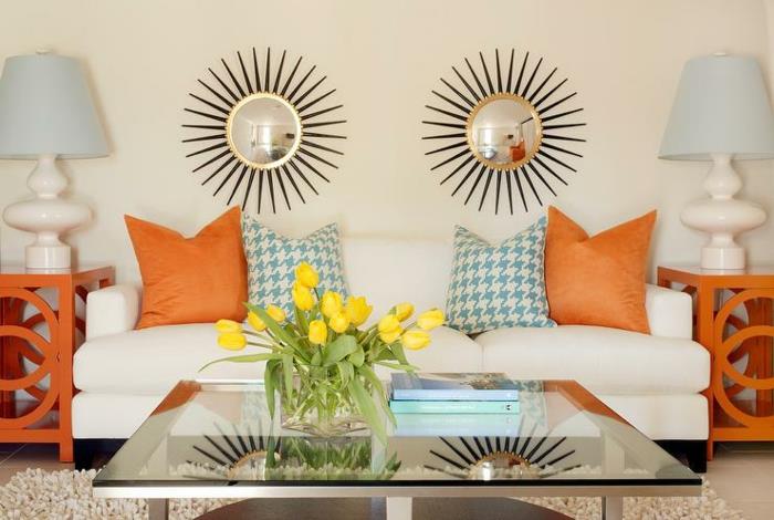 du saulės veidrodžiai virš baltos sofos su spalvingomis pagalvėlėmis ir grynuolių raštais