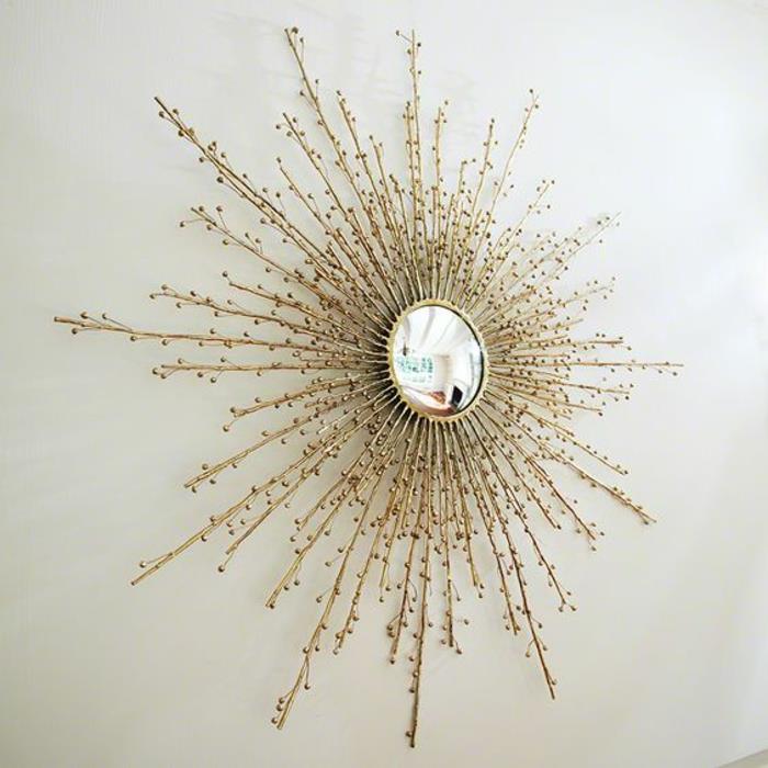 saulės veidrodis su stilizuotais smulkiais spinduliais, kad atspindėtų šviesą ant baltos sienos