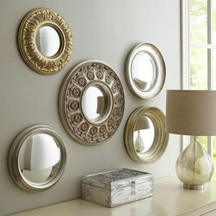 raganinis veidrodis 5 apvalios formos ant pilkos sienos virš baltos įėjimo spintelės