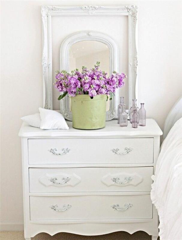 bela nočna omarica s predali, pistacijevo zeleno vedro, šopek rož, prazen okvir in ogledalo deco, belo perilo