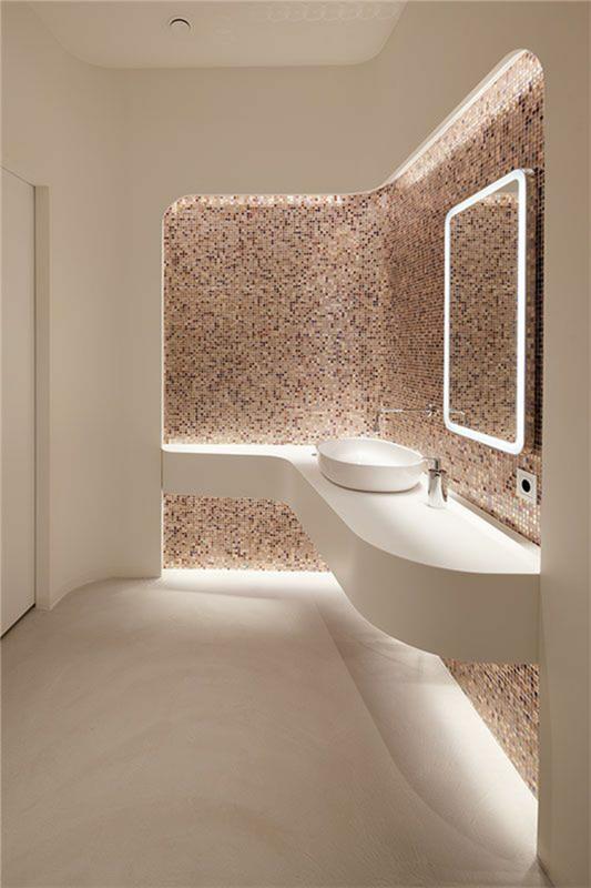Aşağıda pembe ve beyaz aydınlatmalı lavabo alanında mozaikli banyo aynası