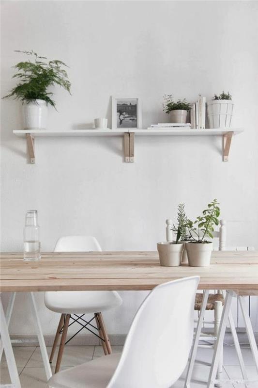 Arredamento sala da pranzo con un tavolo di legno e sedie bianche, parete con mensola e piante verdi