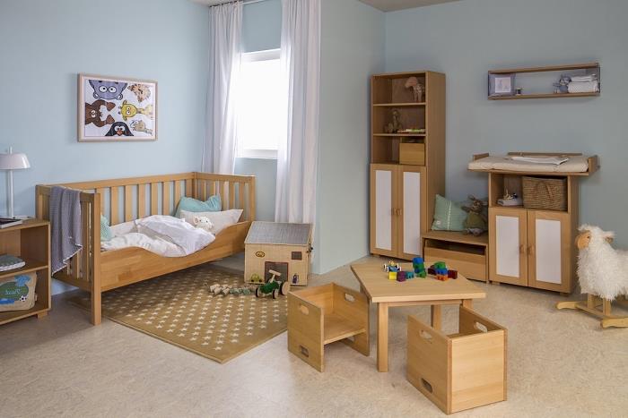 Pastel mavi duvarlar ve bej zemin üzerinde yeni doğan hafif ahşap mobilyalar ile çocuk yatak odası deco modeli