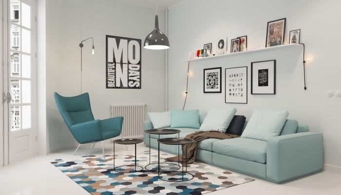 Pastel mavi kanepe ve ördek mavisi sandalyede İskandinav mobilyaları, geometrik desenli halı, siyah sehpalar, beyaz raf, fotoğraf saklama yeri, gri tasarım sarkıt lamba