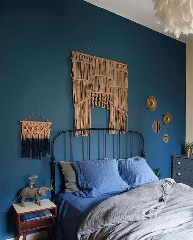 stensko ozadje v modri barvi in ​​stensko vzglavje makrame v sivi in ​​modri spalnici, obesek iz belega perja