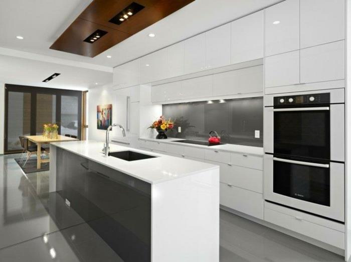 sijoče sive ploščice, majhne svetlobne pike okrogle oblike, strop delno izdelan v rjavi, belo lakirani kuhinji, otoška kuhinja