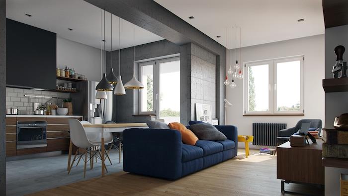 pigus tamsiai mėlynos sofos modelis prieš pilką, baltą ir medinę virtuvę, tradicinė svetainė su šviesiu parketu ir dizainerių baldais, pramoninio dekoro elementais