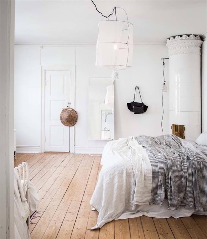 tasarımcı yatak odasında İskandinav mobilyalı dekor, beyaz ve siyah nevresimler, hafif parke, orijinal beyaz sarkıt lamba, beyaz şömine