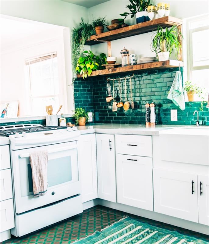 balta ir žalia virtuvė l, su balta pagrindo spintele, žalios spalvos plytelėmis, kaimiškos medinės lentynos, žalias ir baltas kilimas, žali augalai