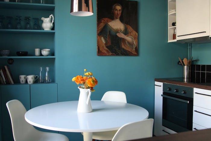 virtuvės modelis atviras valgomajam, fasadas, baltas stalas ir kėdės, siena iš naftos mėlynos spalvos