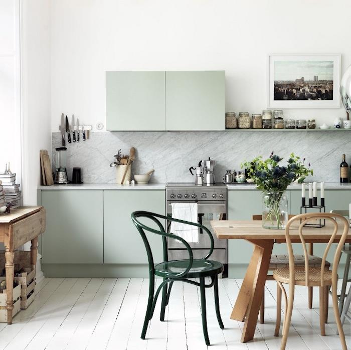 pastelno zelena sprednja kuhinja, senčnik celadon, lesena miza in stoli, pobeljen parket, smaragdno zelen stol siv marmor s čopičem, starinsko pohištvo
