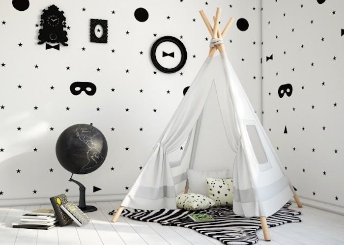 İskandinav tasarımı çocuk odasında İskandinav grafik duvar kağıdı, beyaz duvar, yıldızlar ve maskeler deseni, çocuk çadırı, zebra halısı, badanalı parke