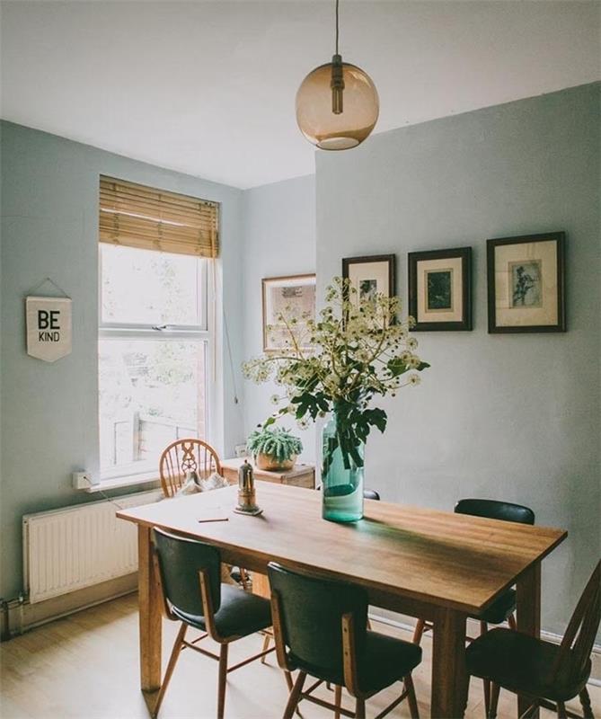 ideja za jedilnico s stenami iz barve verdigris, senčnik celadon, miza in leseni ter črni stoli, viseča svetilka, svetel parket