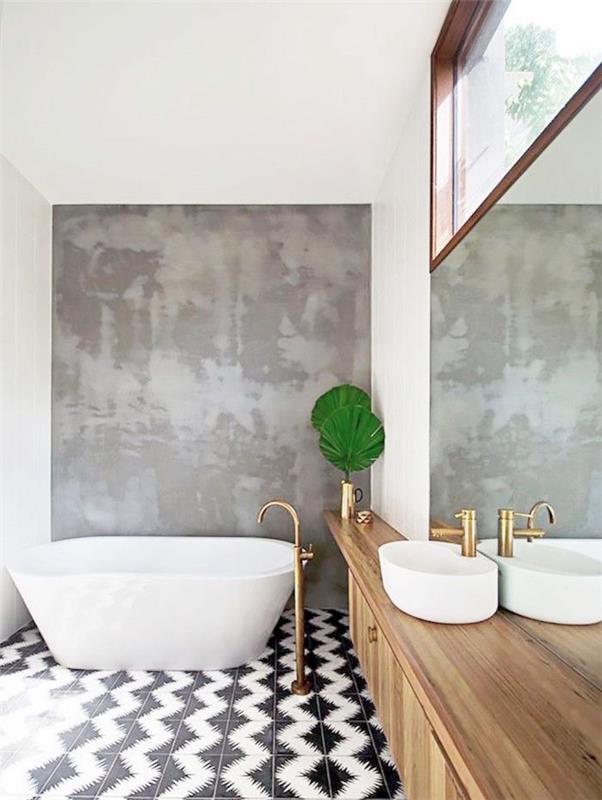 Deco ideja odprte kopalnice s samostoječo kadjo in mini umivalnikom na leseni omari ter zlato pipo s črno -belimi keramičnimi tlemi in sivo voskano betonsko steno