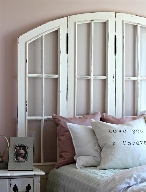 bele reciklirane bele okne, bele posteljnine z rožnatimi okrasnimi blazinami, vintage nočna omarica