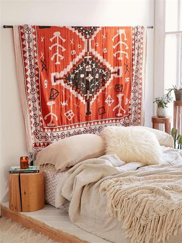 oranžno vzglavje iz tkanine z aztečnimi vzorci, belo in bež perilo, lesena nočna omarica, dekoracija spalnice