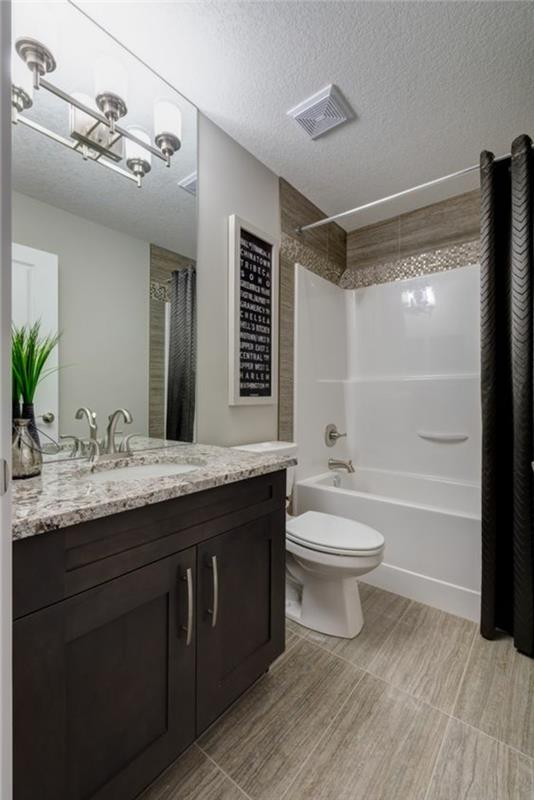 mažas vonios kambarys su rudais baldais ir plytelėmis išklota kriaukle, imituojančia marmurą