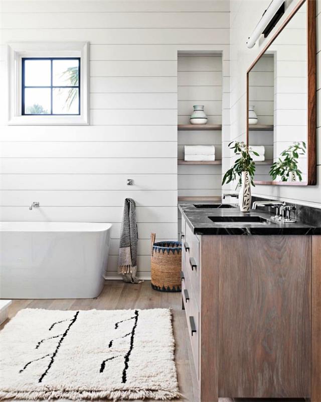 kopalnica v belem podeželskem stilu z obloženimi stenami, naravnimi materiali in etničnim tekstilom za prijeten ambient v kopalnici