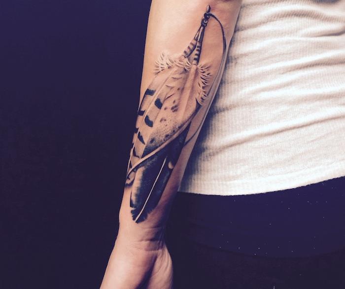 tetovaža s perjem, obleka v beli brezrokavniki in črne hlače, tetovaža na roki v obliki perja