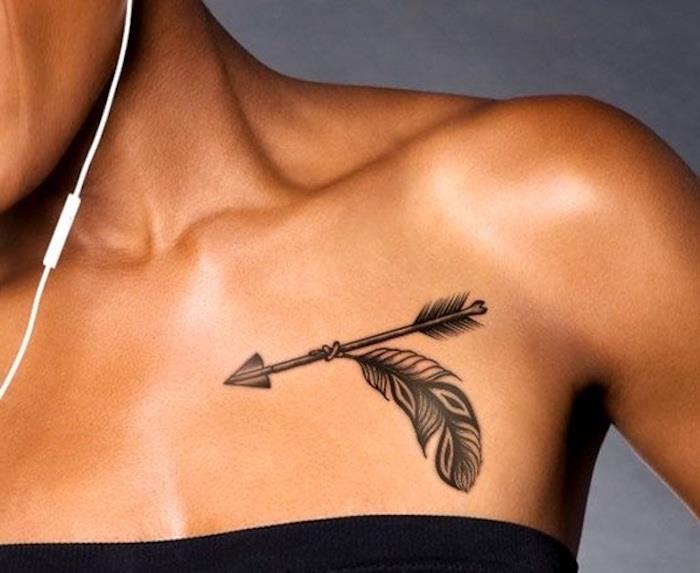 elegantna tetovaža v črni barvi, puščica in pero, indijski simboli, tetovirani pod ključno kostjo mlade ženske
