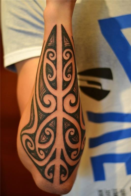 kabile adamı dövmesi, kolda etnik desenler ve parşömenlerle sembolik dövme