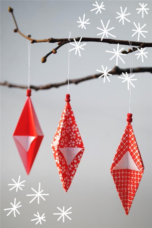 origami lankstė geometrinius kalėdinius papuošalus, pagamintus iš atspausdinto popieriaus su raudonais ir baltais raštais, pakabinamus ant dekoratyvinės šakos