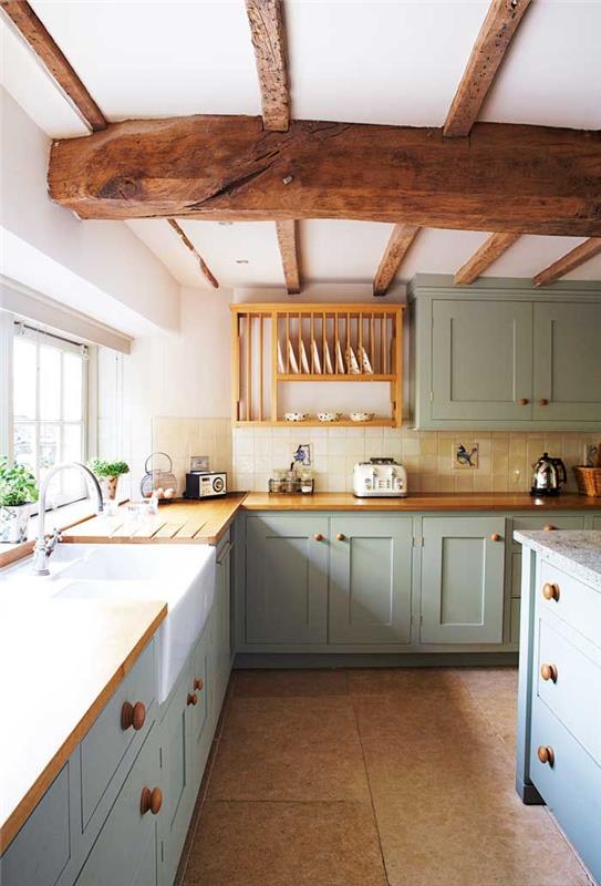 Kuhinjski model v angleškem podeželskem slogu s ploščicami v ozadju svetlo sive kuhinjske omare lesene plošče in izpostavljeni leseni tramovi
