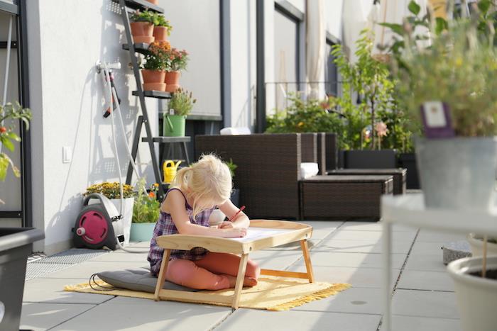 montessori pedagogika sode, veiklos stalas piešimui sode, pilka pagalvėlė, geltonas žaidimų kilimėlis