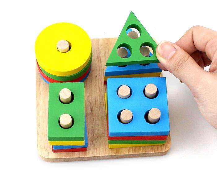 ilişkilendirme oyunu, ahşap bir tahta üzerinde renkli geometrik figürlerin düzenlenmesi, bir kreşte Montessori pedagojisi