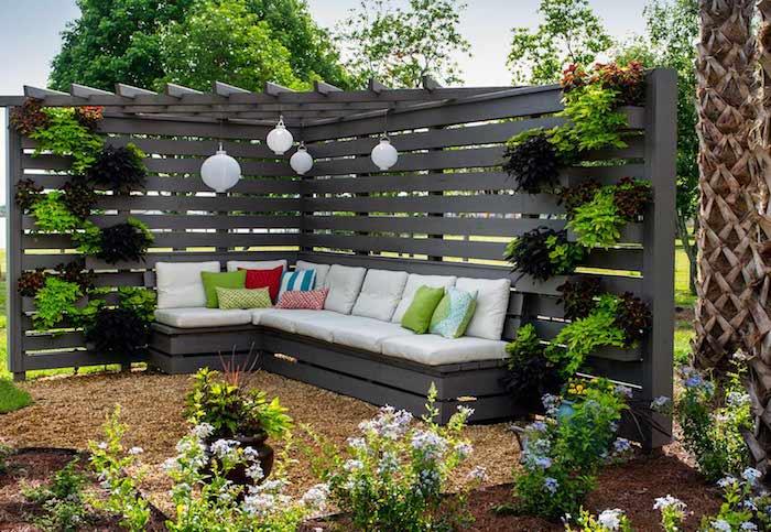 dikey bitki duvarlı modern pergola ve beyaz koltuk minderi ve renkli dekoratif minderler, bahçe bitkileri ile gri bir kanepe