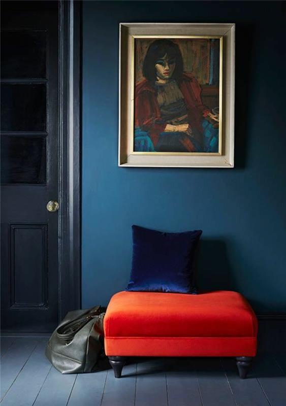 anties mėlyna siena, moters portretas, raudona taburetė ir mėlyna pagalvėlė