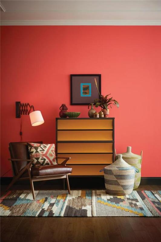koralno rdeča stena, večbarvna preproga, košare in stol iz usnja in lesa